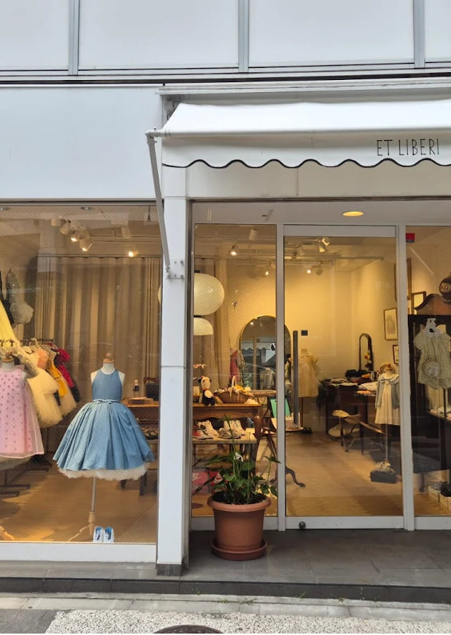 Storefront with mannequins wearing colorful dresses displayed in a window