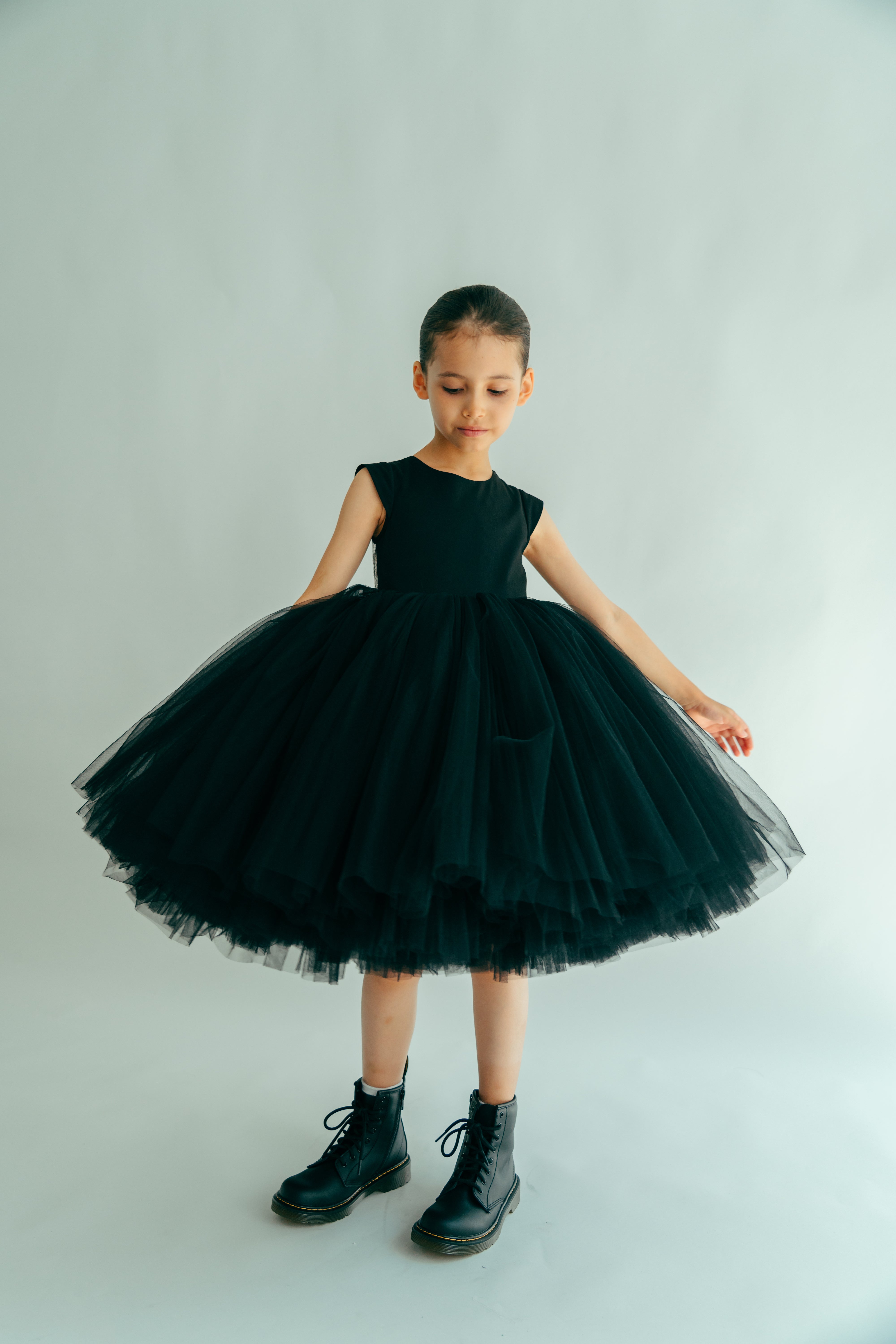 A young girl wearing a black, maxi skirt dress with sequins, paired with black boots.