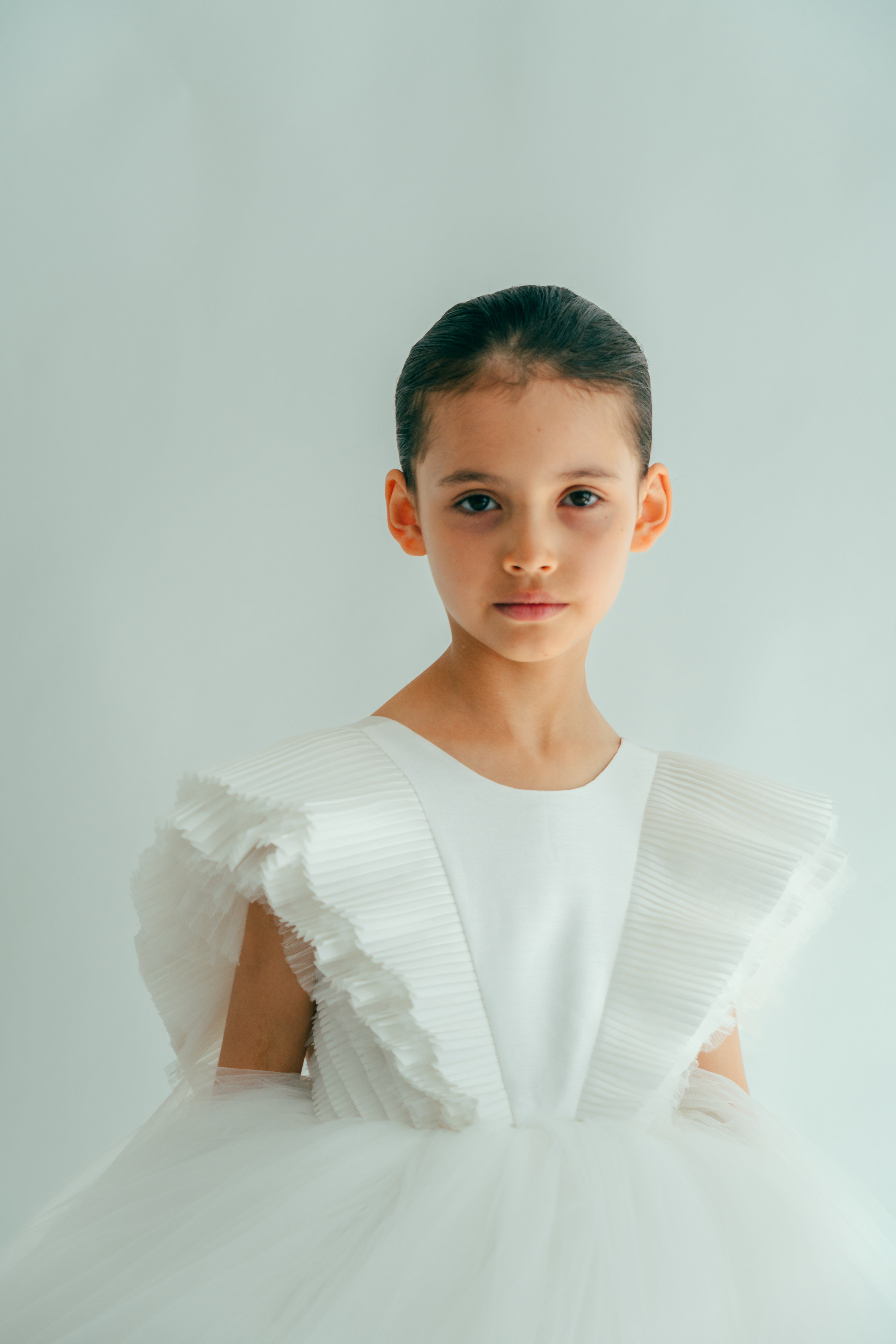 Young girl posing in an elegant white dress with voluminous sleeve details